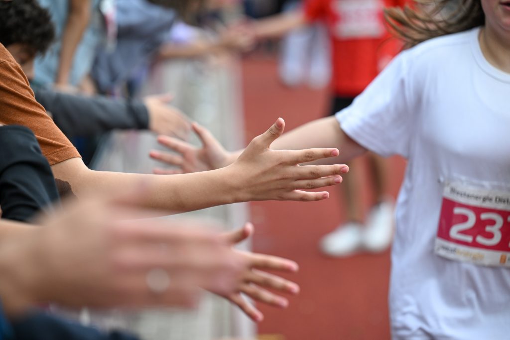 Händer-Abklatschen von Zuschauern und einem Läufer oder einer Läuferin