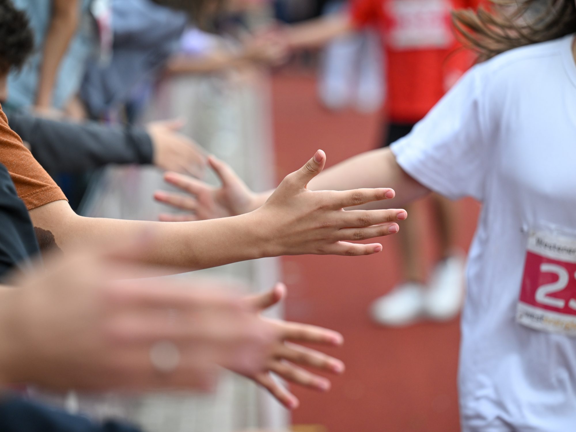 Händer-Abklatschen von Zuschauern und einem Läufer oder einer Läuferin