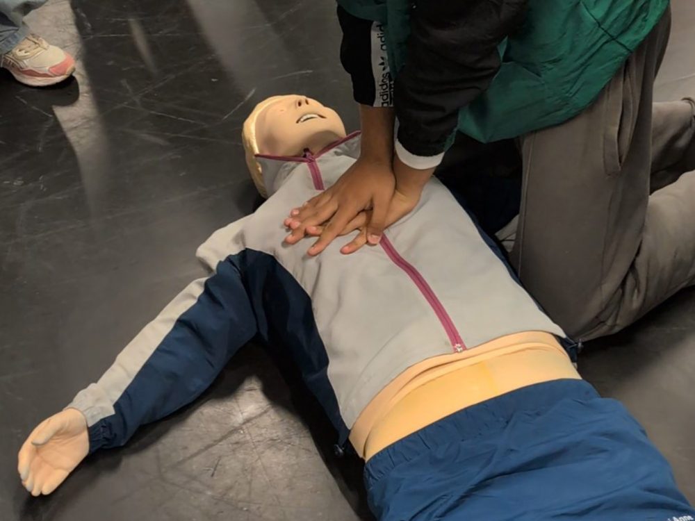 Schüler führt Herzdruckmassage an Übungspuppe aus.