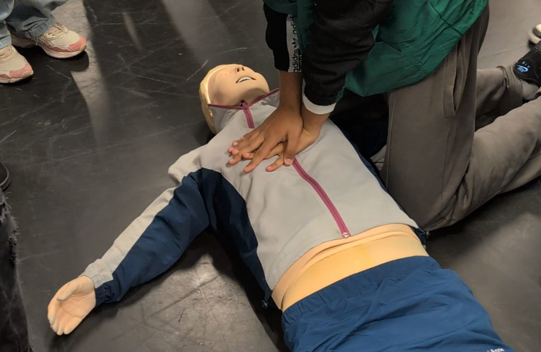 Schüler führt Herzdruckmassage an Übungspuppe aus.